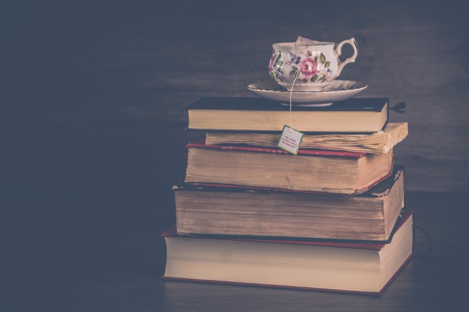 Stack of classic romance novels with a vintage teacup