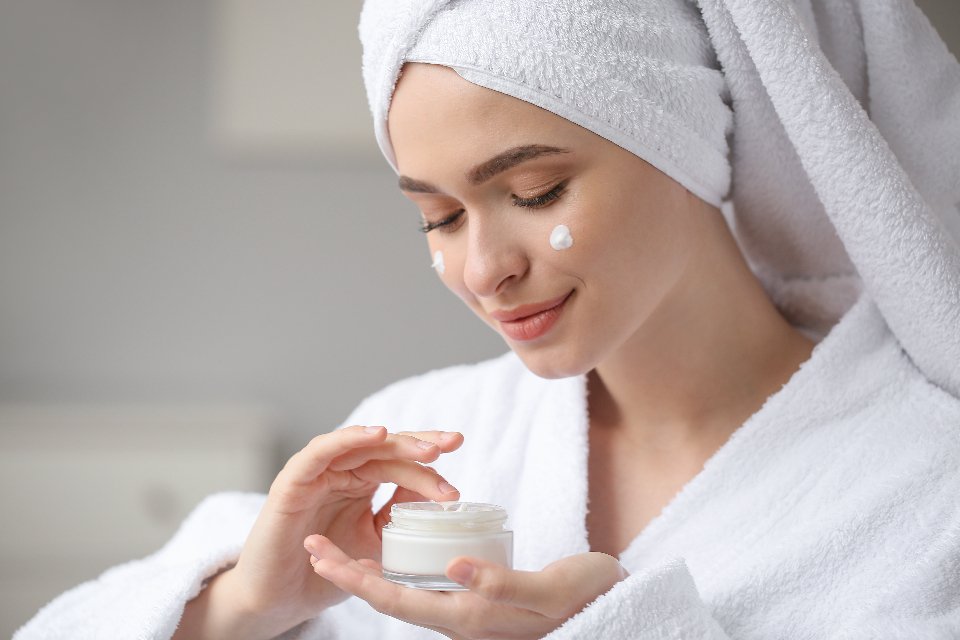 Woman applying face cream after a shower as part of a skincare routine