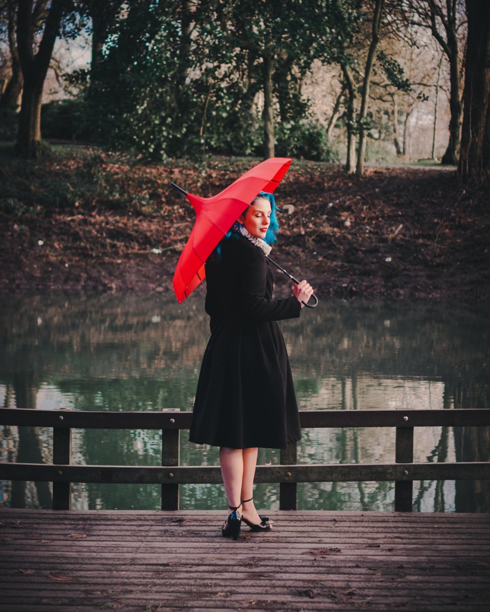 Woman in a black wool coat holding a red umbrella