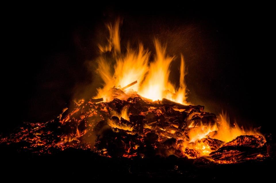 Bright bonfire flames against a dark night sky