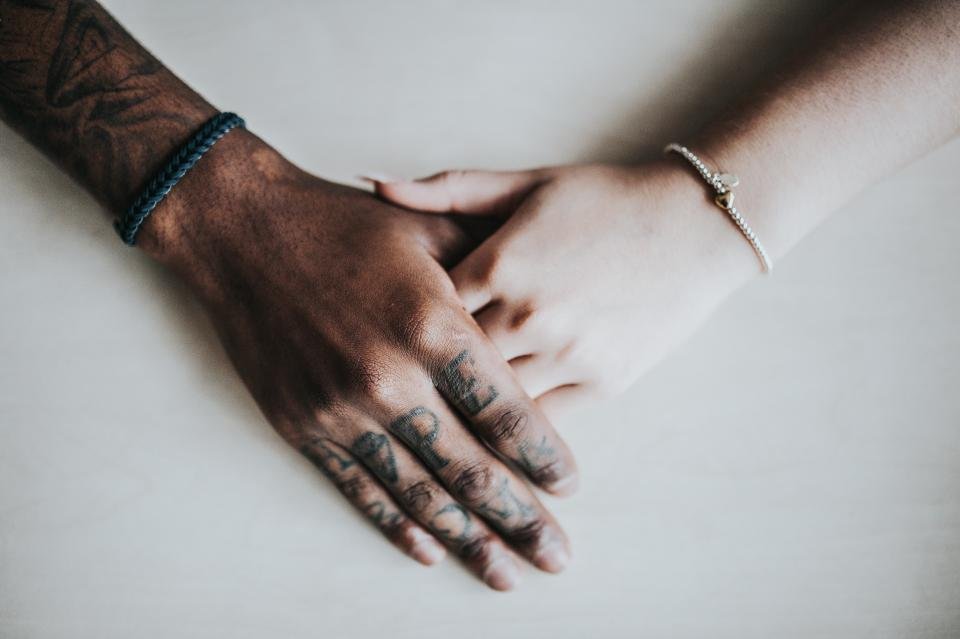 Hands with delicate bracelets resting on a white table