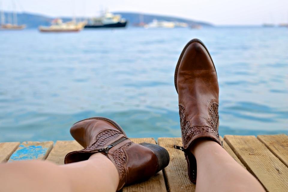 Brown leather ankle boots on a wooden dock by the water