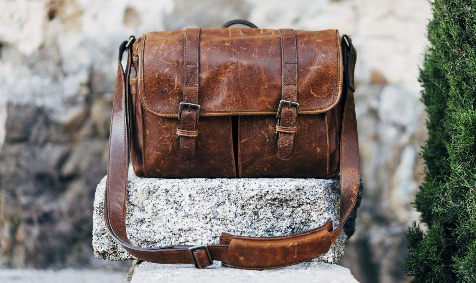 Brown leather bag resting on a stone wall outdoors