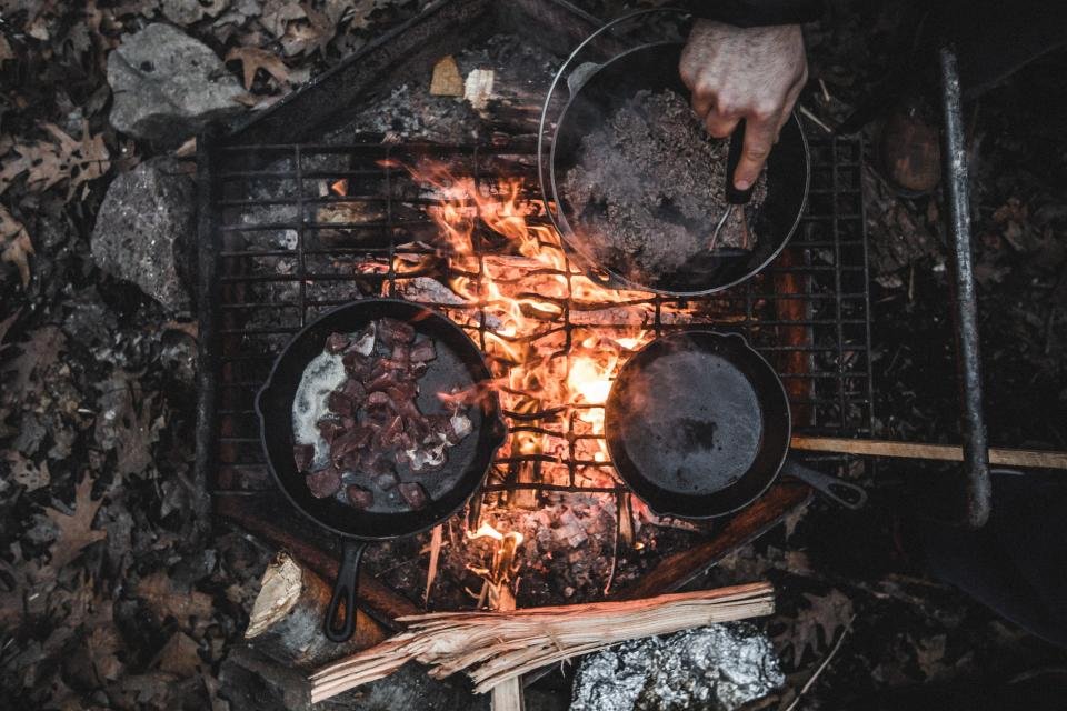 Cast iron pans over a campfire grill, an idea for outdoor gifts for dad