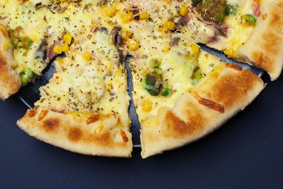 Pizza ovens make crisp cheese pizza sliced on a dark table