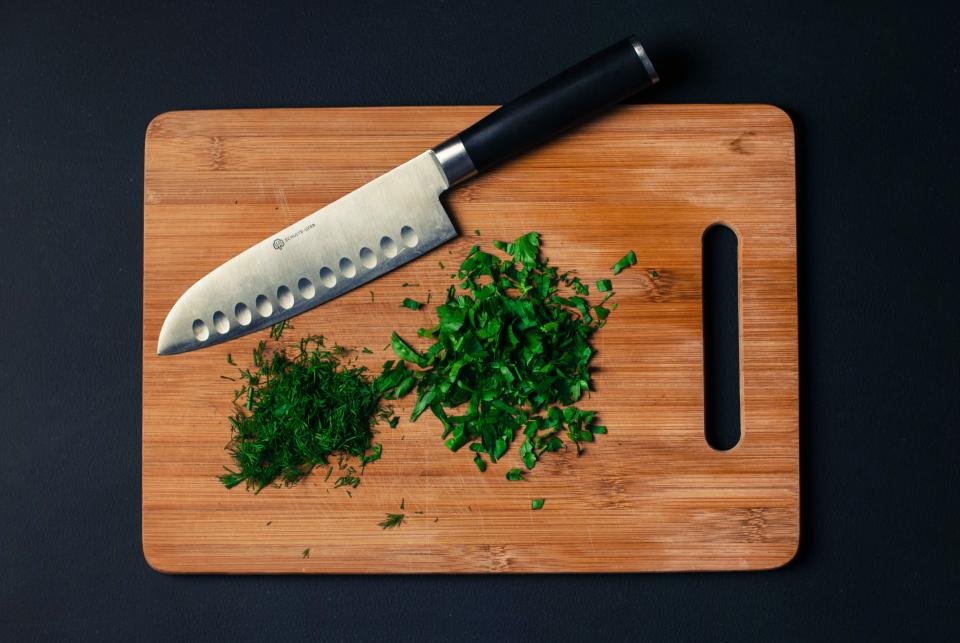 A chef knife and chopped herbs on a cutting board, a classic idea for gifts for home cooks