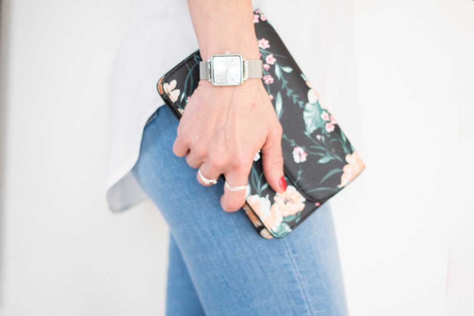 Woman holding a floral clutch bag with a silver watch