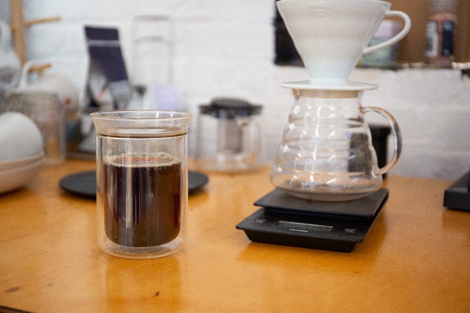 Coffee brewing on a digital scale beside a glass carafe
