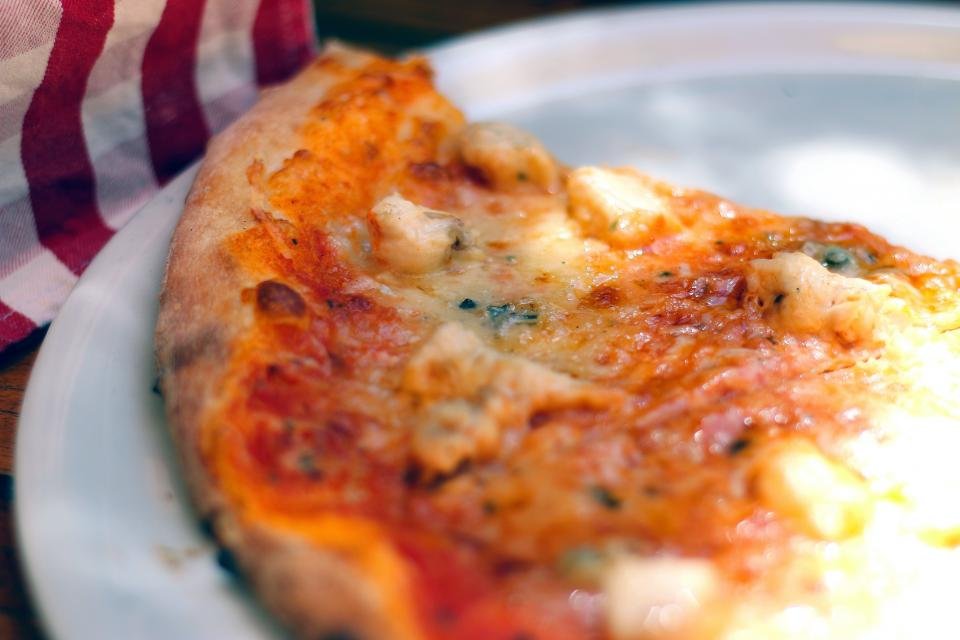 Slice of pizza with a crispy charred crust on a plate