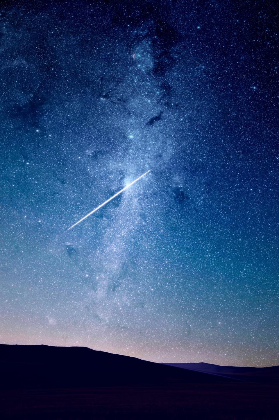 Shooting star across a blue night sky for a daily horoscope reading