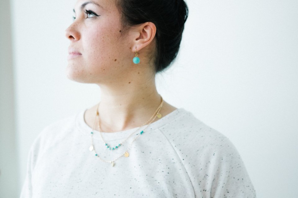 Woman wearing a dainty necklace with matching drop earrings