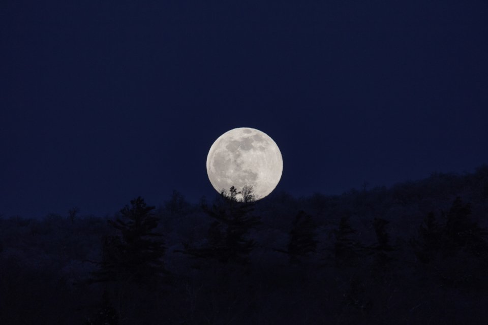 Full moon over a dark winter landscape in December