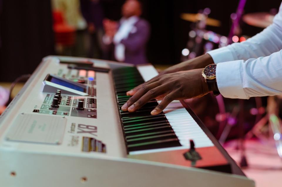 Hands playing a digital keyboard on stage, showing the versatility of the best digital pianos