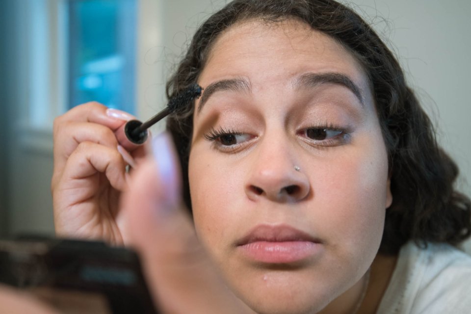 Woman using eyebrow products in a mirror