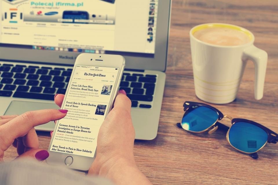 Reading news on a phone and laptop while learning how to spot fake news
