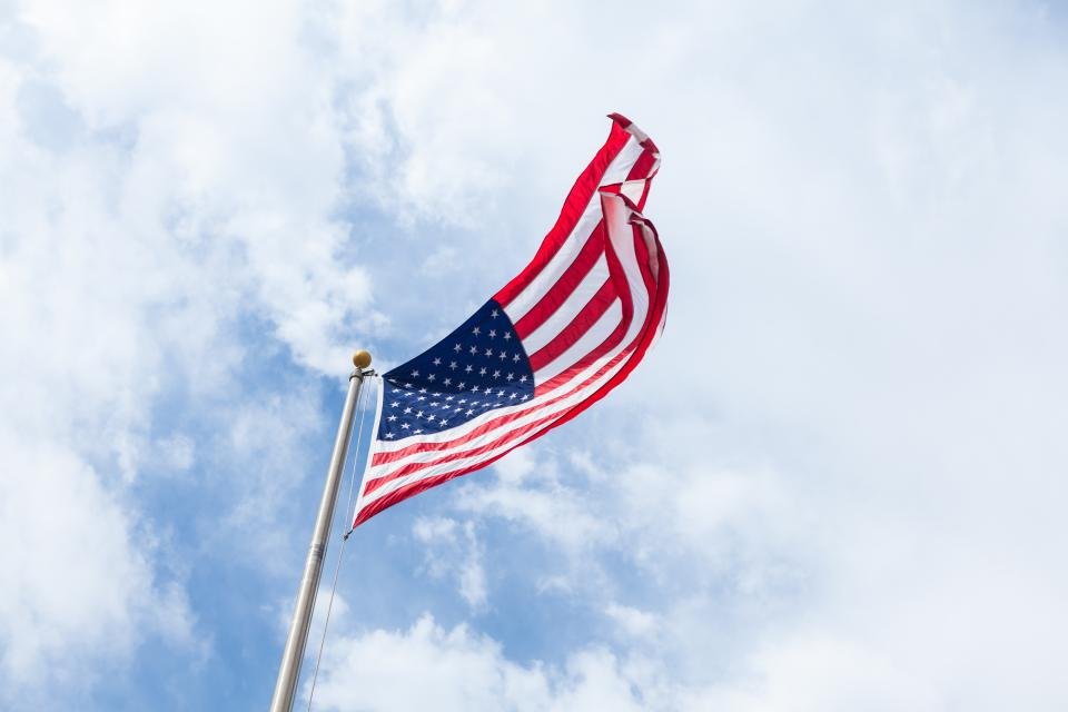 American flag waving against white clouds