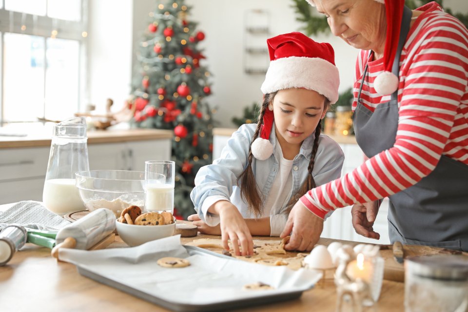 Gifts for grandma ideas shown by a grandmother baking holiday cookies with her granddaughter