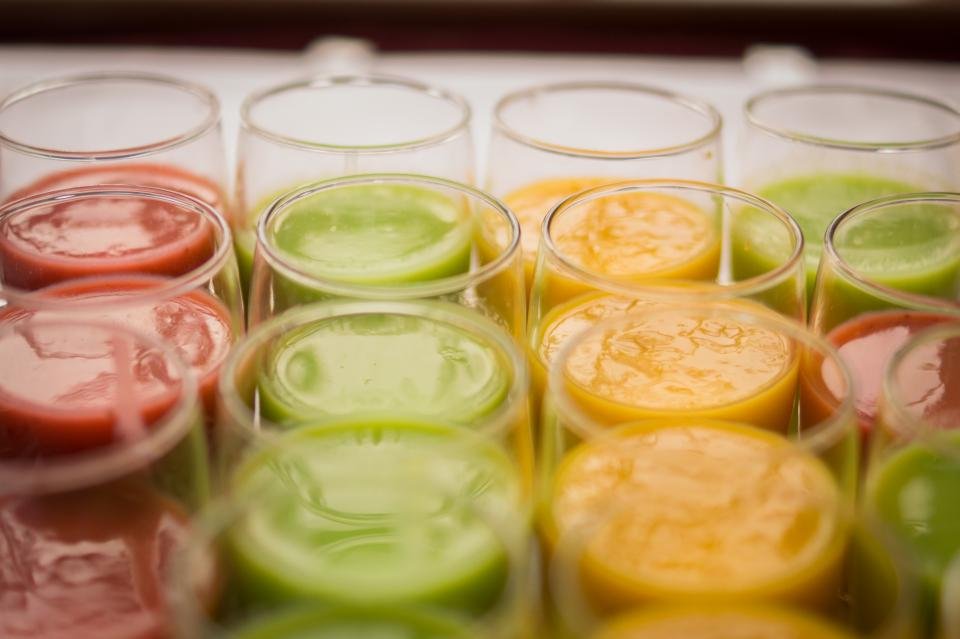 Rows of colorful green and orange smoothies in glasses