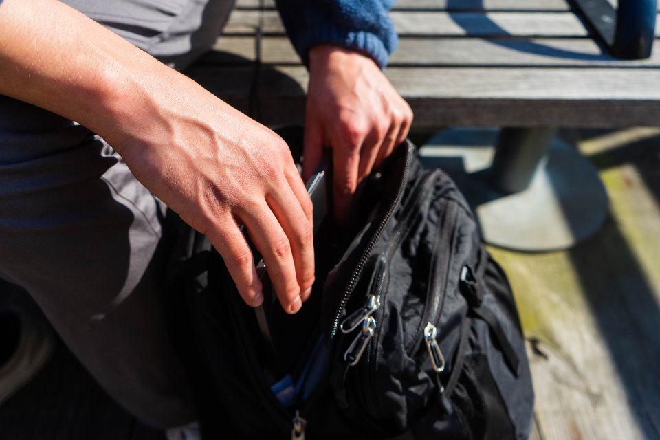 Hands opening a black backpack with laptop compartment