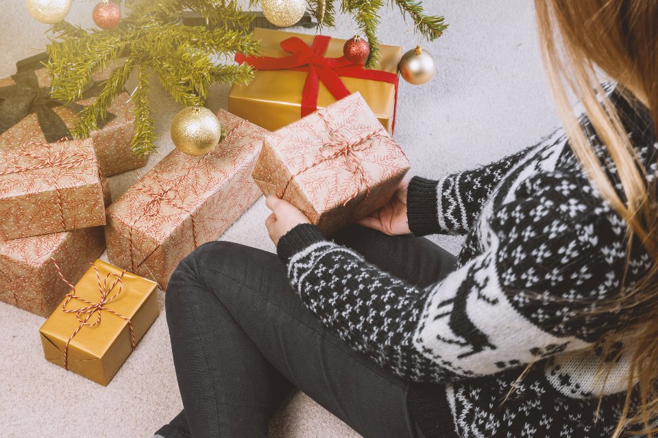 Holiday party outfits: a cozy patterned sweater beside wrapped gifts
