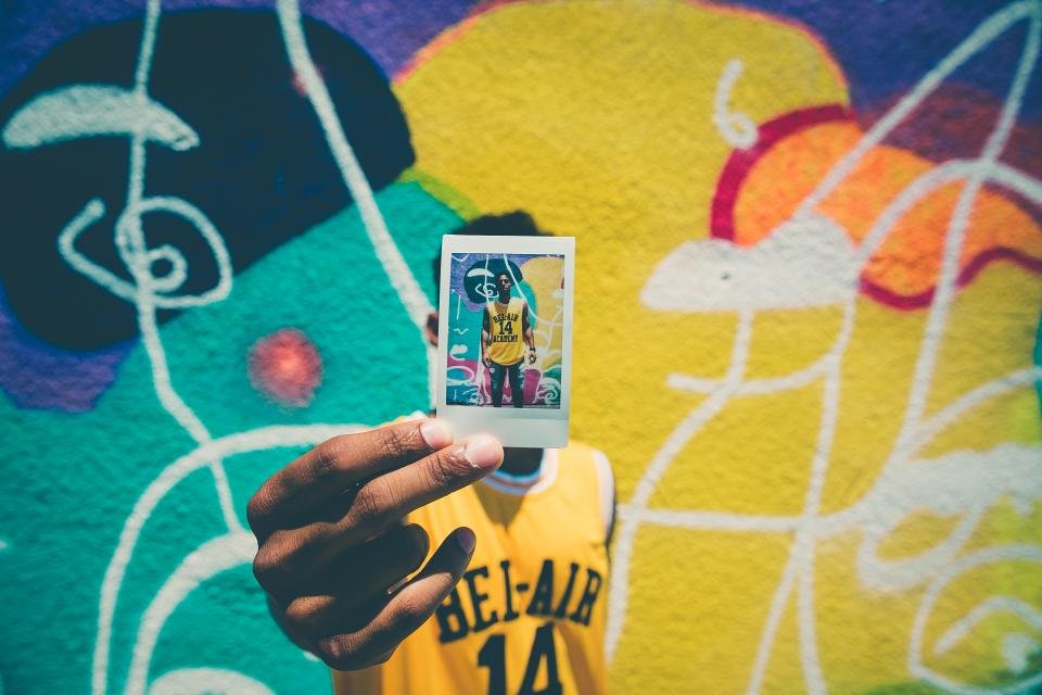 A colorful instant film print held up in the city