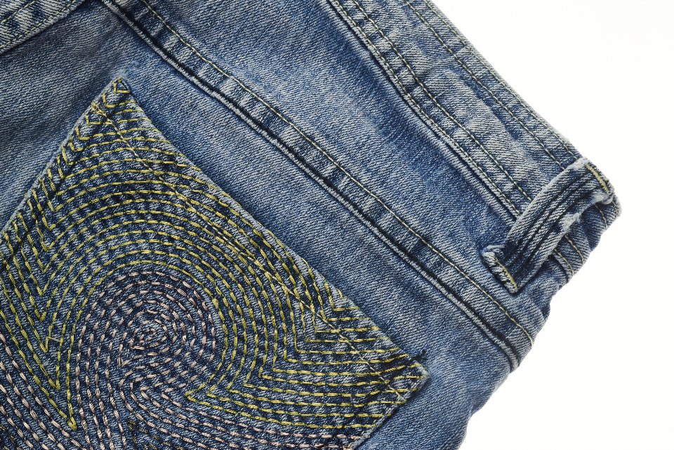Back pocket stitching detail on blue jeans