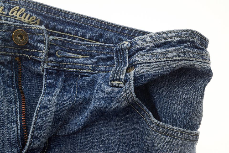 Close up of a high rise jeans waistband and button