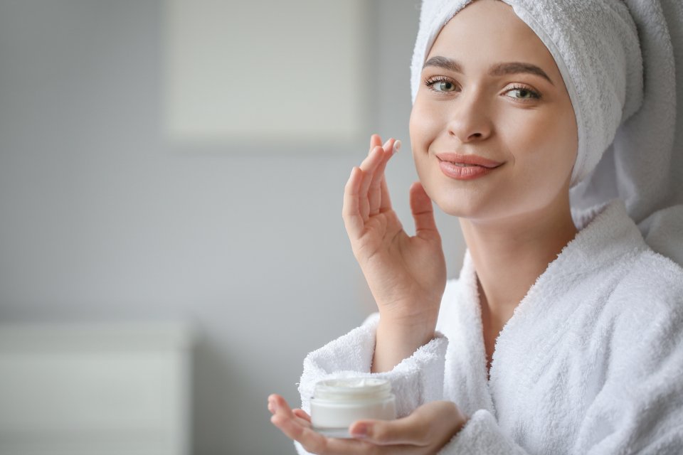 Woman applying korean skincare serum in a bright bathroom