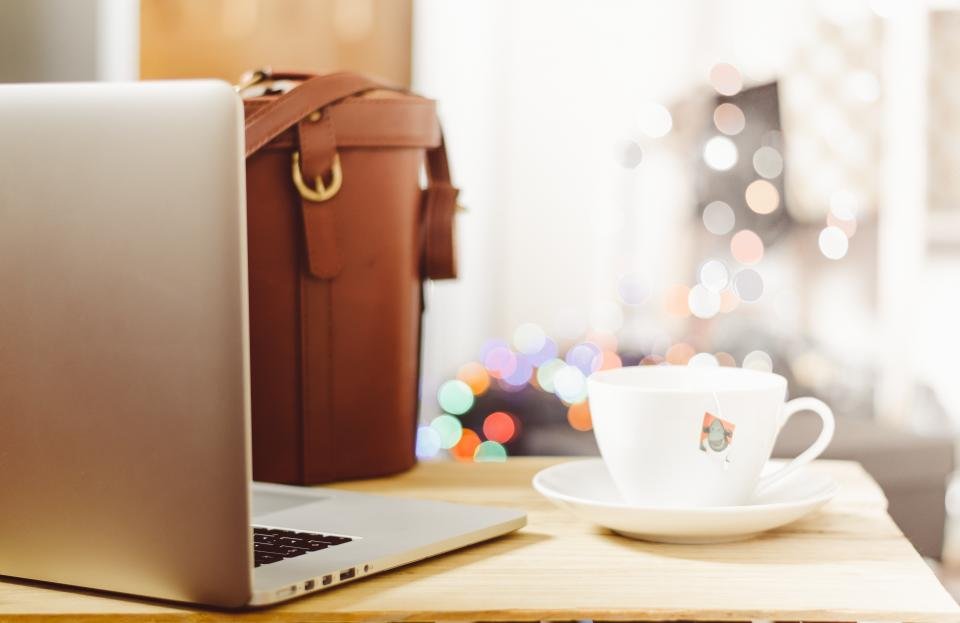 Laptop beside a leather bag and coffee, a look at the best laptop bags for women