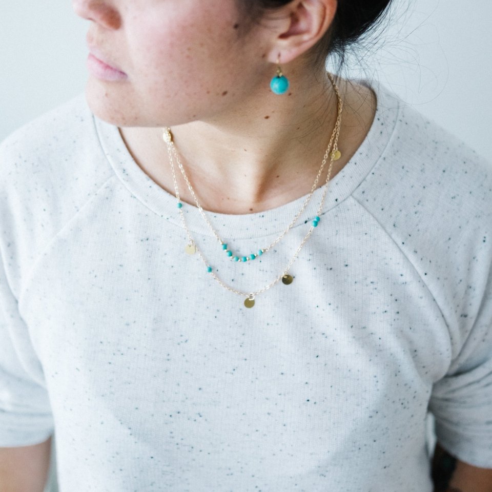 Best layering necklaces: dainty gold chains layered over a white top