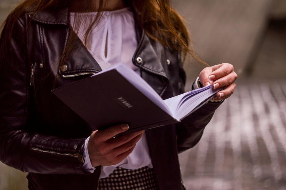 Woman in a leather jacket reading a book