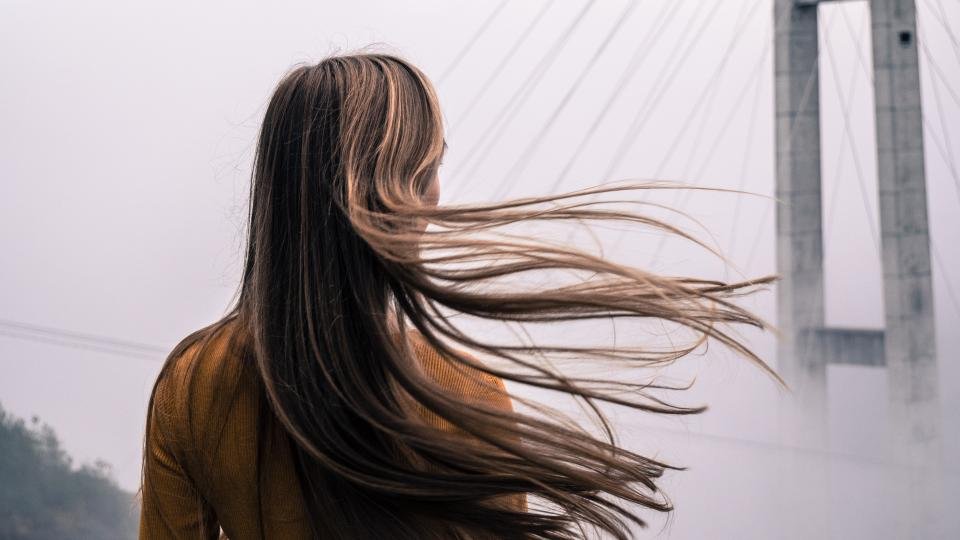 Best luxury hair oils: long glossy dark hair moving in the wind