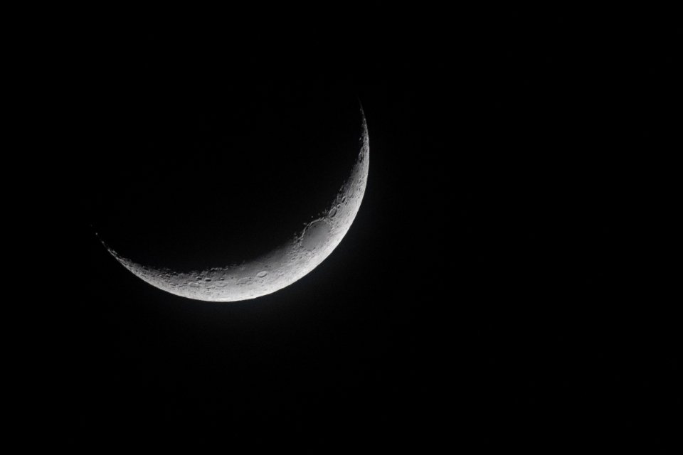 Thin crescent moon against a black night sky