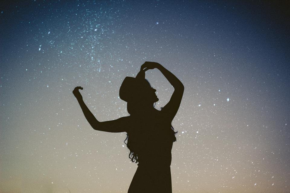 Silhouette of a woman dancing under a starry sky