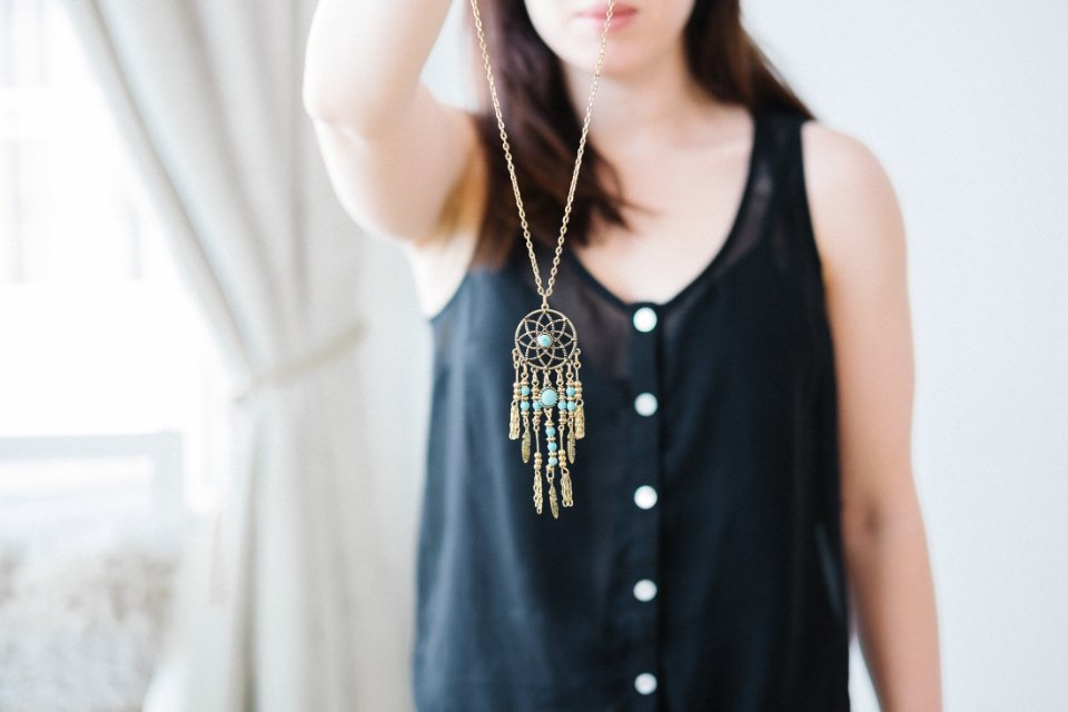 Long pendant necklace worn over a black sleeveless top