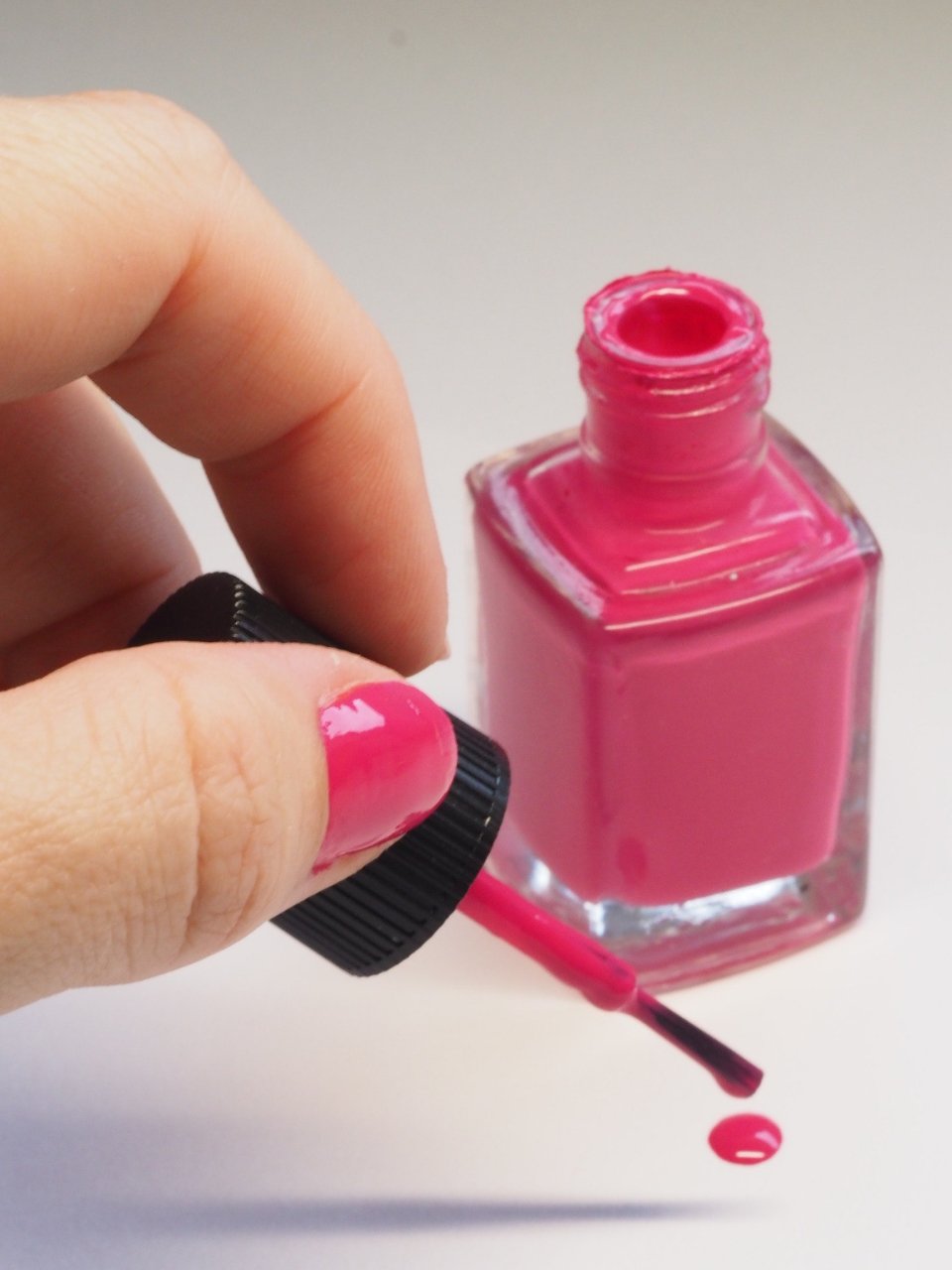 Hand holding a pink bottle from one of the best nail polish brands