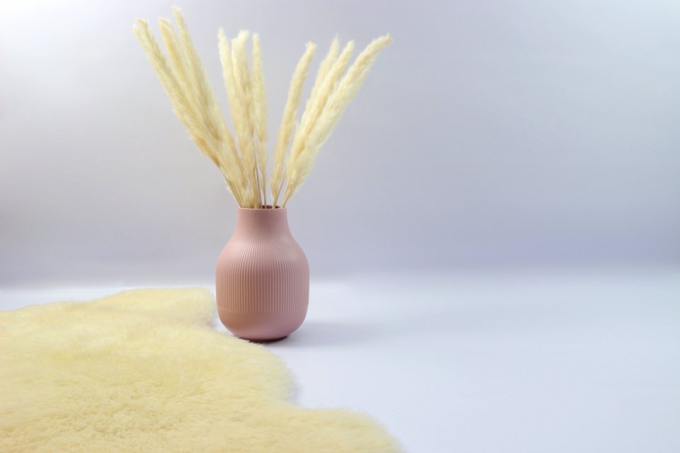 Pink vase with dried grasses, styled like a reed diffuser on a table