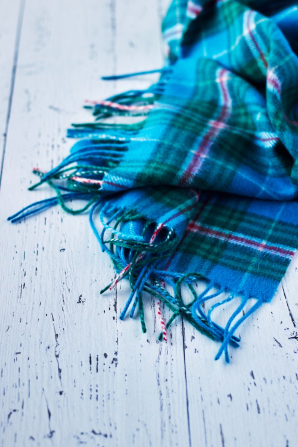 Blue plaid scarf with fringe on a white wooden table