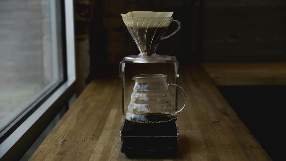Coffee makers brewing a pour over carafe on a wooden counter