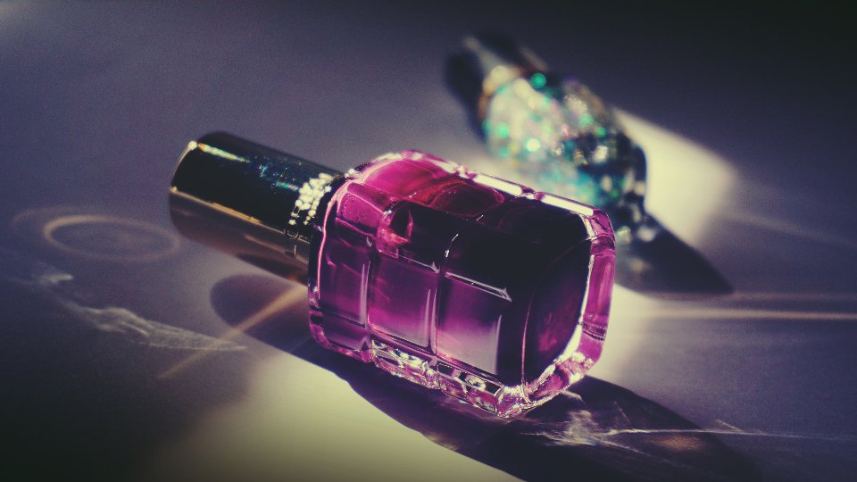 Purple nail polish bottle on a glossy surface