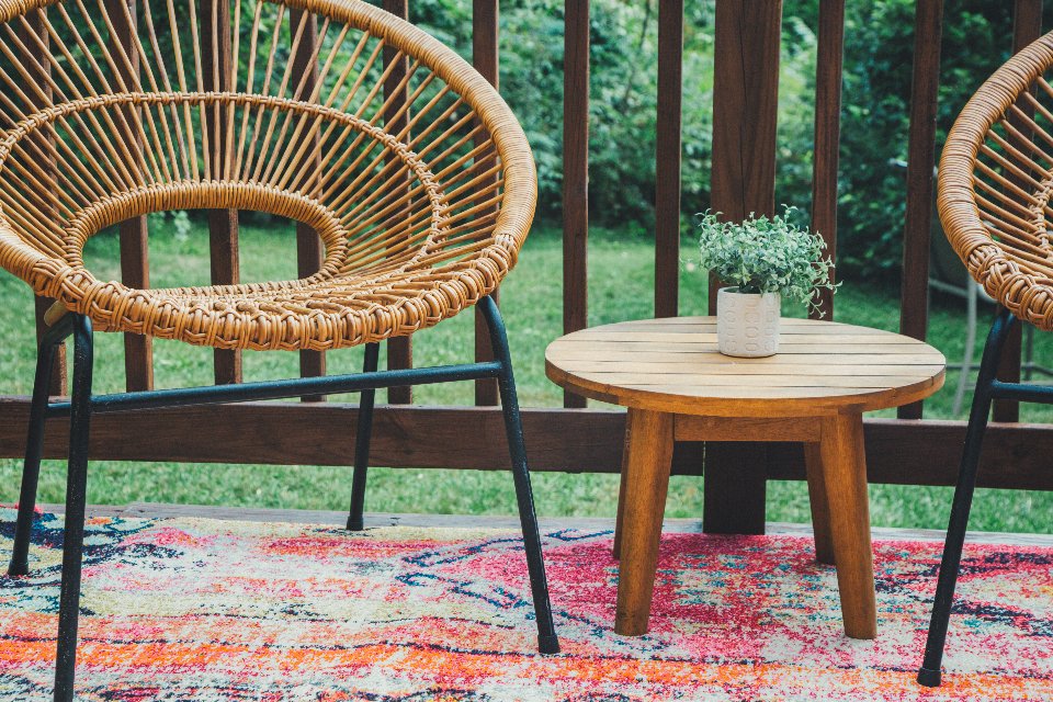 Rattan patio chairs and a wooden side table on a deck