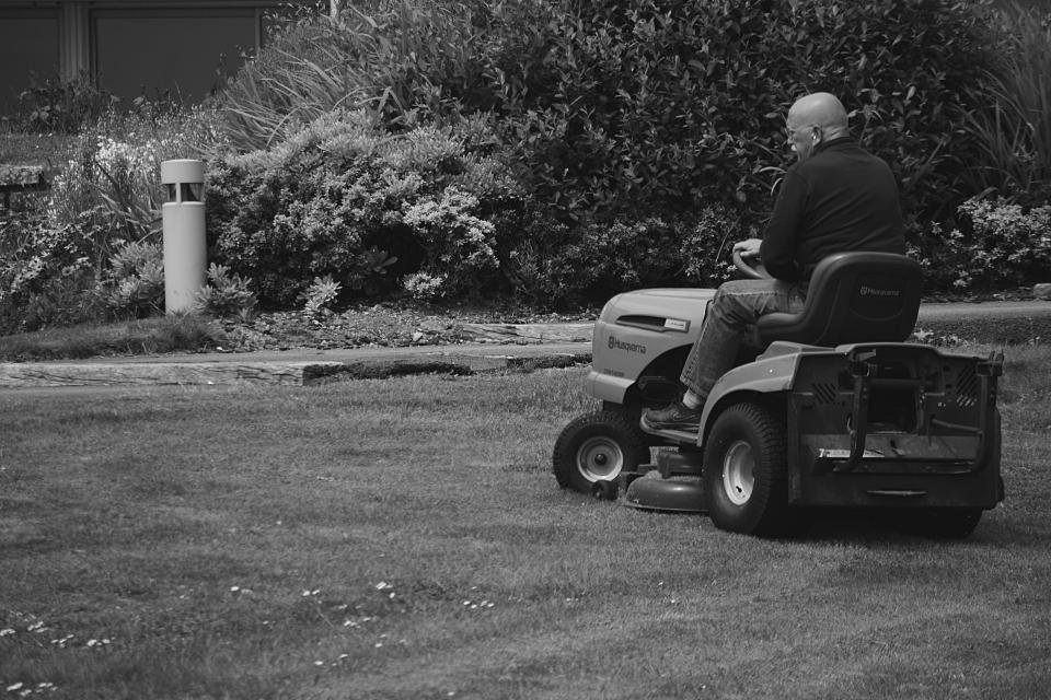 Traditional riding mower cutting grass in a garden