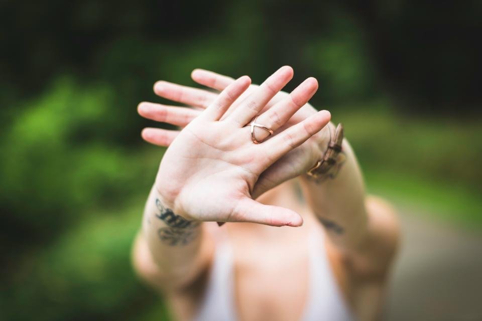 Hands wearing rings against a green background