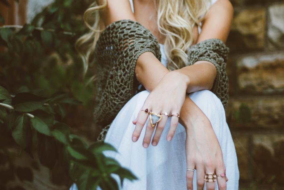 Woman wearing delicate gold rings while sitting outdoors