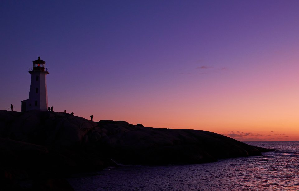Lighthouse silhouetted against a colorful sky at dusk