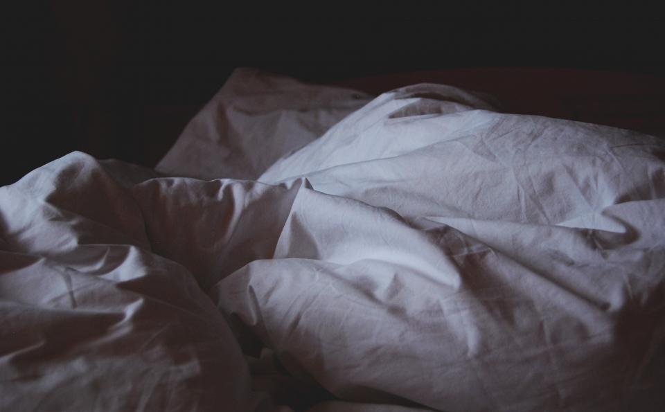 Soft rumpled pillows and duvet on a bed at night