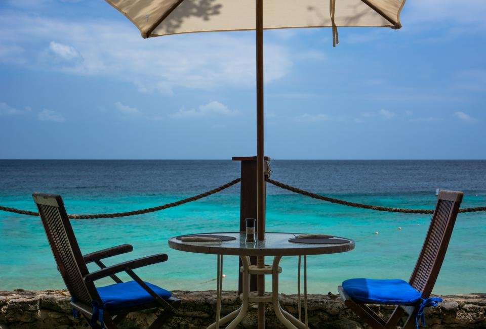 Bistro table and chairs under an umbrella by the sea