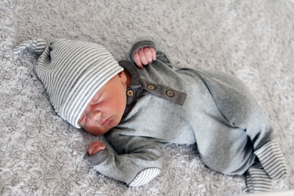 Sleeping newborn in a knit hat, a reminder of thoughtful gifts for new moms