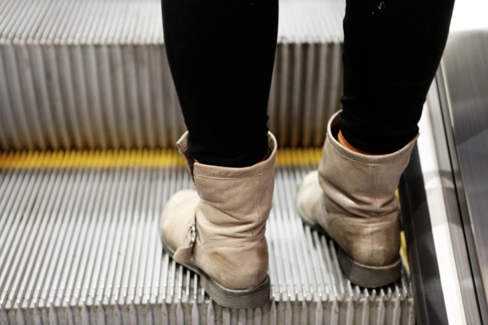 Slouchy beige boots on a city escalator in autumn