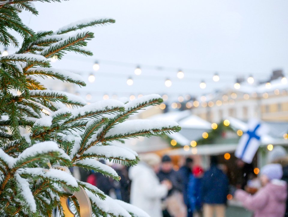 Snowy fir branches and festive lights above Christmas market stalls